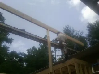 Carpenter setting a ridge beam over a new addition frame — Ice Dam Removal by Roofing Brothers in Mc Louth
