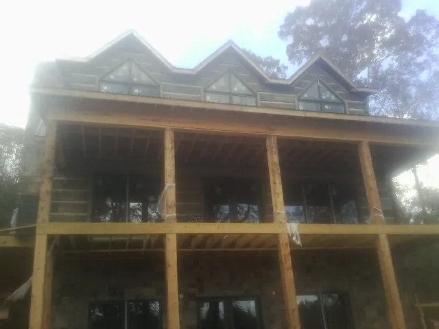 Dormers and porch framing on a large log home under construction — Roof Coating work by our crew in Mc Louth