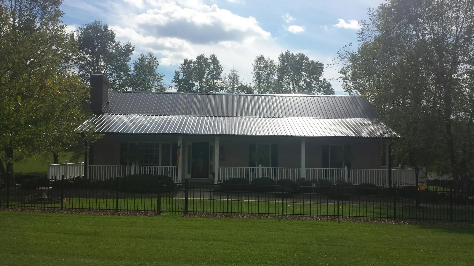 Gray metal roof on a brick ranch with a full width front porch — Gutter Guard Installation work by our crew in Mc Louth
