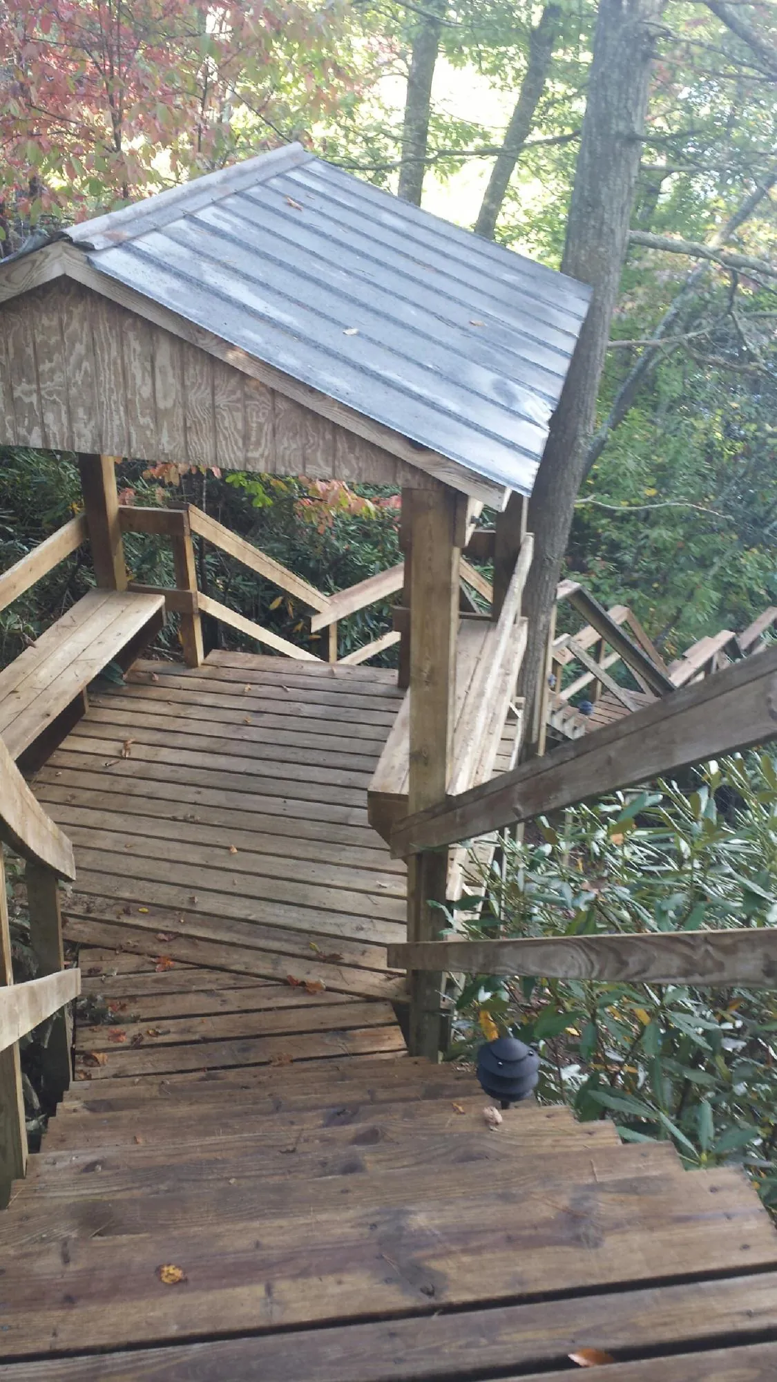 Metal roofed shelter over wooden steps on a wooded walkway — Skylight Repair & Installation work by our crew in Mc Louth