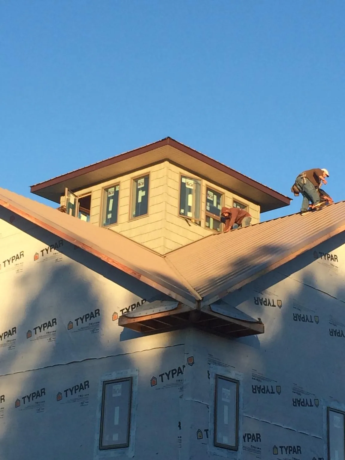 Roofers working around a rooftop cupola on a new metal roof at sunset — Roof Waterproofing in Mc Louth by Roofing Brothers